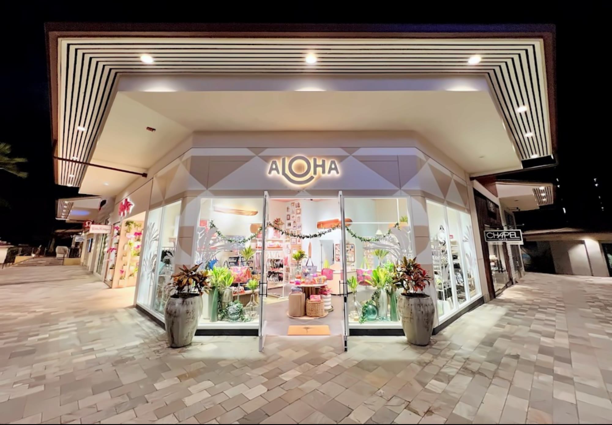 A Breen-built retail storefront lit at night, with ALOHA over the entry