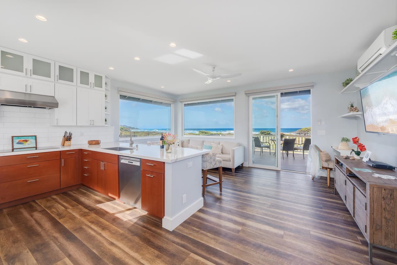 A bright kitchen with warm wood cabinets opening to an ocean view