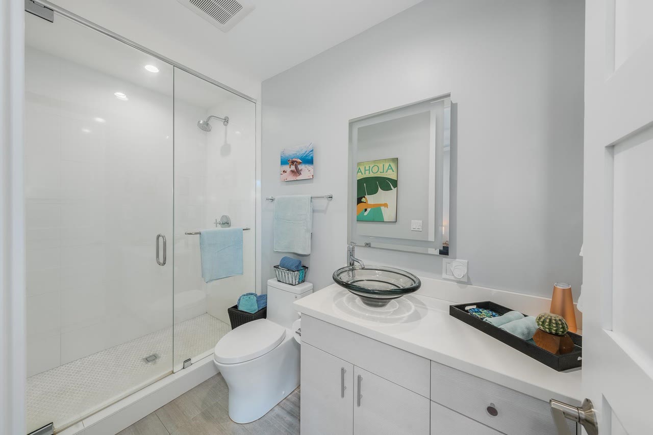A white guest bath with a glass shower and vessel sink