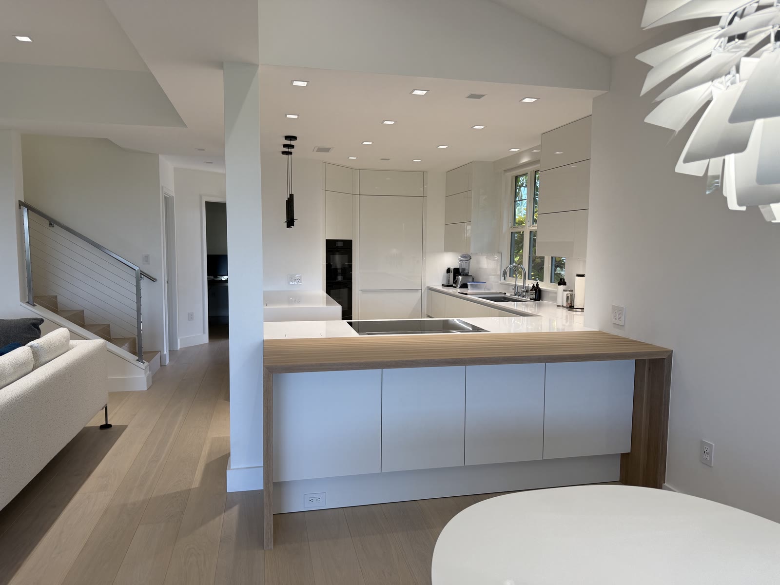 An open white kitchen and living area with a sculptural pendant